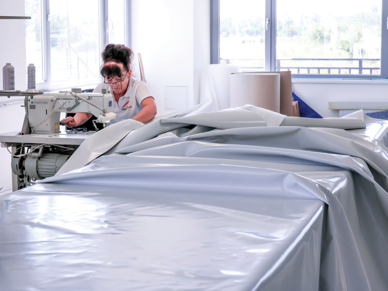 seamstress works on a vinyl cover for climbing mat