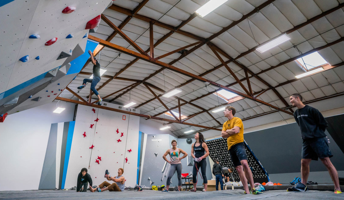 a group of young people in a climbing gym, bouldering together